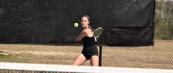 Knights women's tennis player hits the ball during a match. 